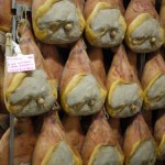 Cured hams hanging in a storage room at a traditional Italian prosciutto factory.