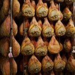 Cured hams hanging in a storage room for aging, showcasing traditional meat preservation techniques.