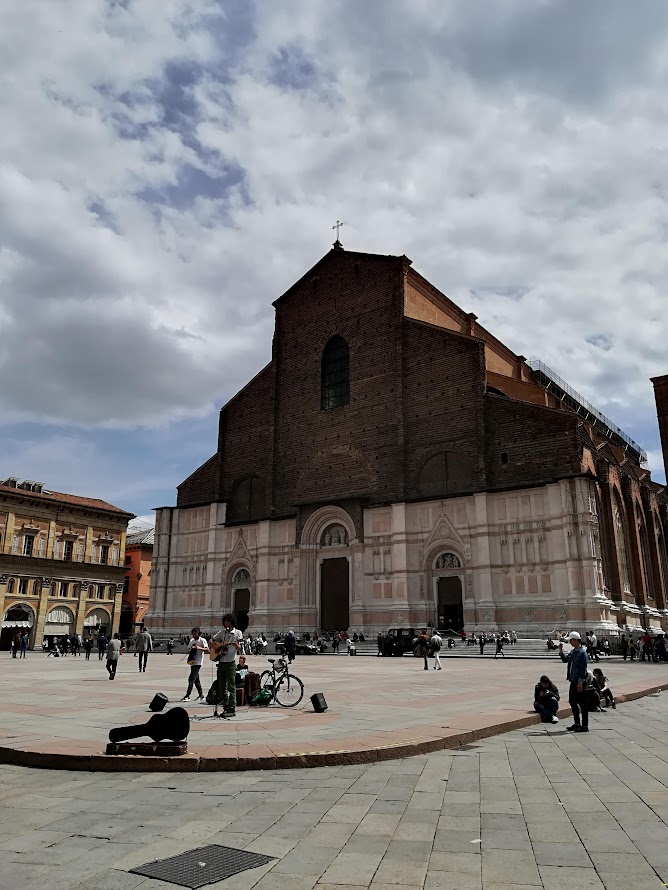 Historic Basilica di San Petronio in Bologna with people gathered outside on a cloudy day.