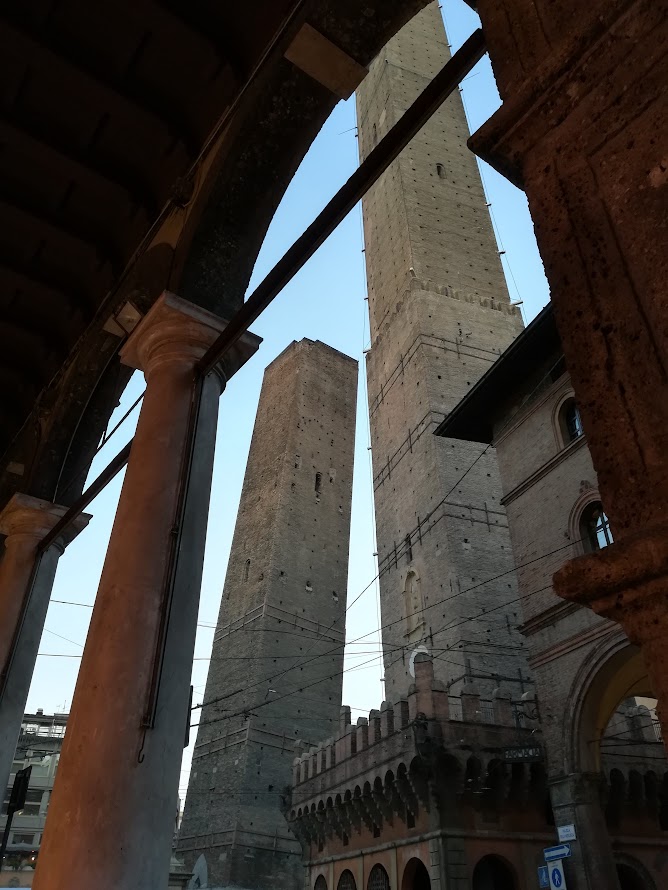 Two medieval towers of Bologna, Italy framed by an archway, showcasing historical architecture and urban scenery.