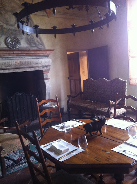 Rustic dining room with wooden table, elegant chairs, and fireplace; medieval-style decor enhances the cozy ambiance.