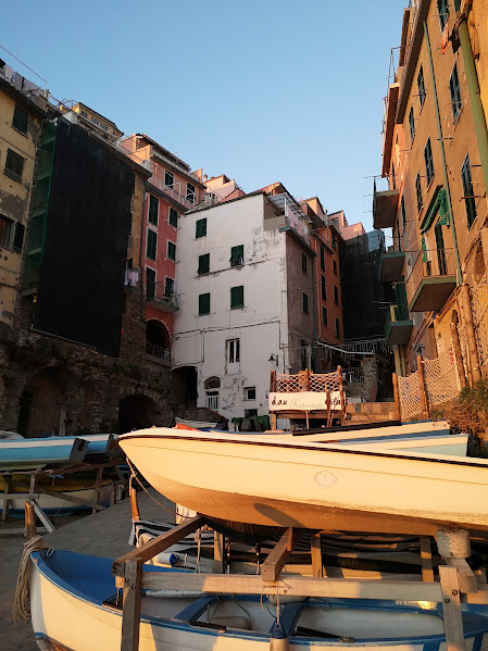 Colorful buildings with moored boats in a picturesque Italian coastal village during sunset.