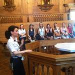 Tour guide explaining history in a wooden lecture hall to an attentive audience.
