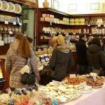Customers browse in a cozy pastry shop with shelves of sweets and a display of assorted baked goods.