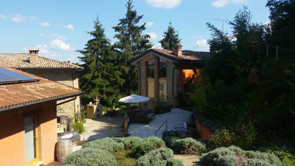 Rustic Italian villa with garden, patio, and lush greenery under clear blue sky, capturing serene countryside ambiance.