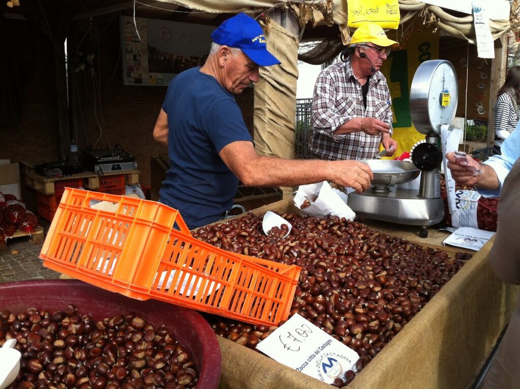 Men selling chestnuts at a market stall with weighing scale, showcasing fresh produce and local trade.