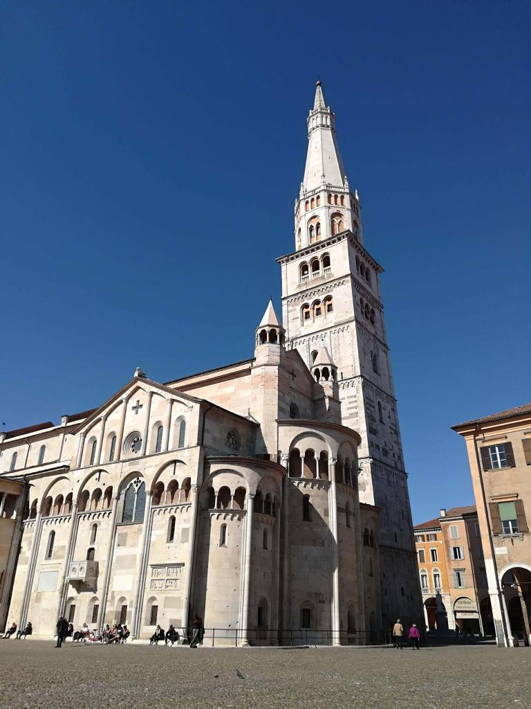 Historic Modena Cathedral and Ghirlandina Tower against a clear blue sky in Modena, Italy.