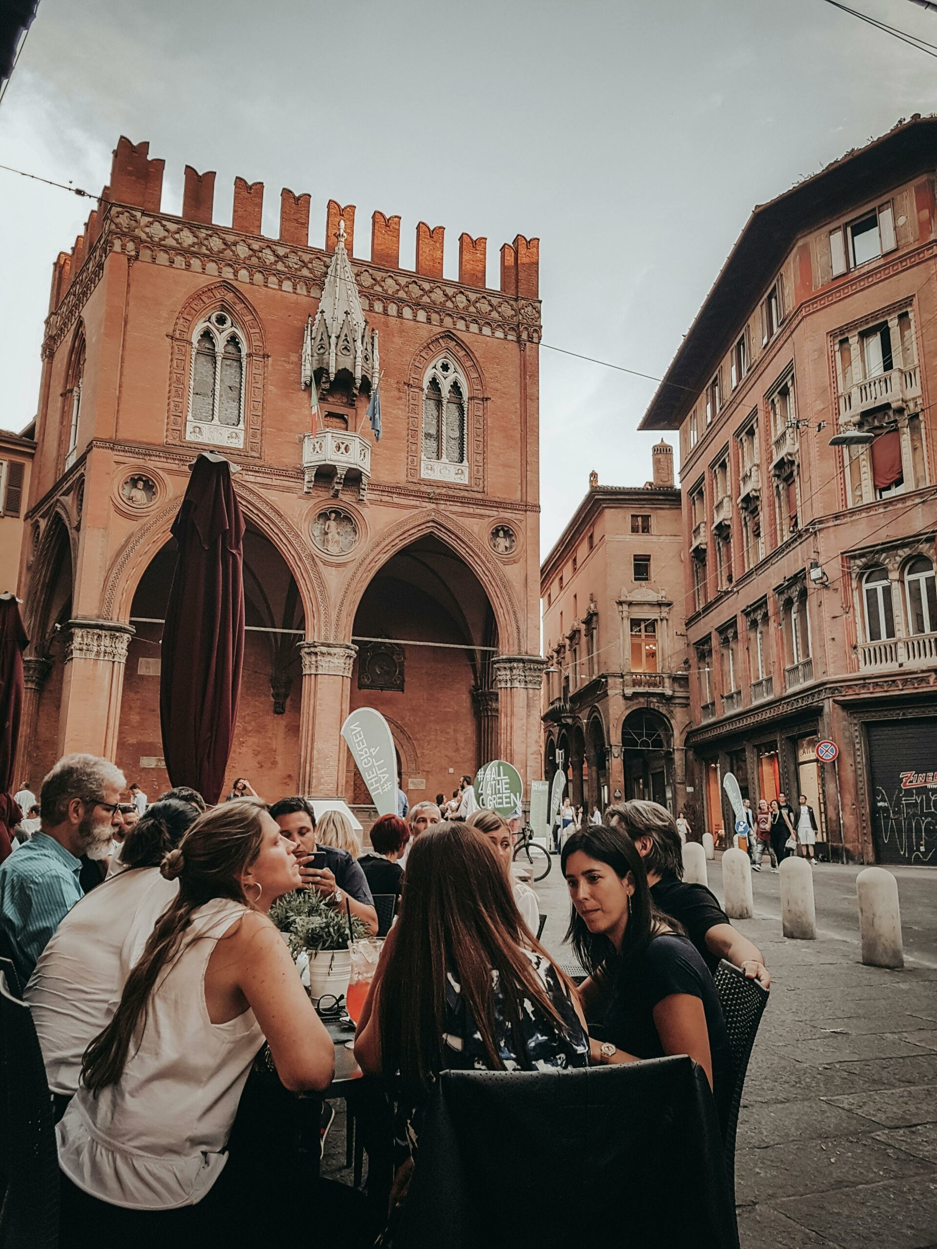 Group dining outside historic building in European city. Medieval architecture and lively atmosphere.