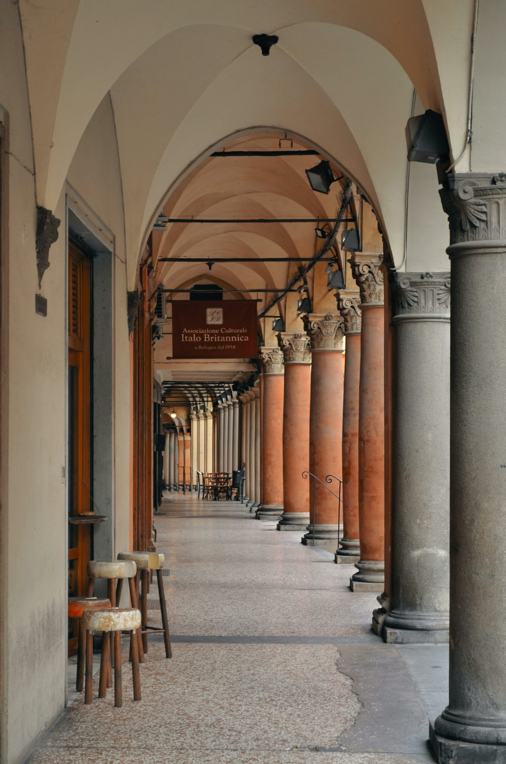 Historic arched walkway with vibrant red columns in Bologna, Italy.