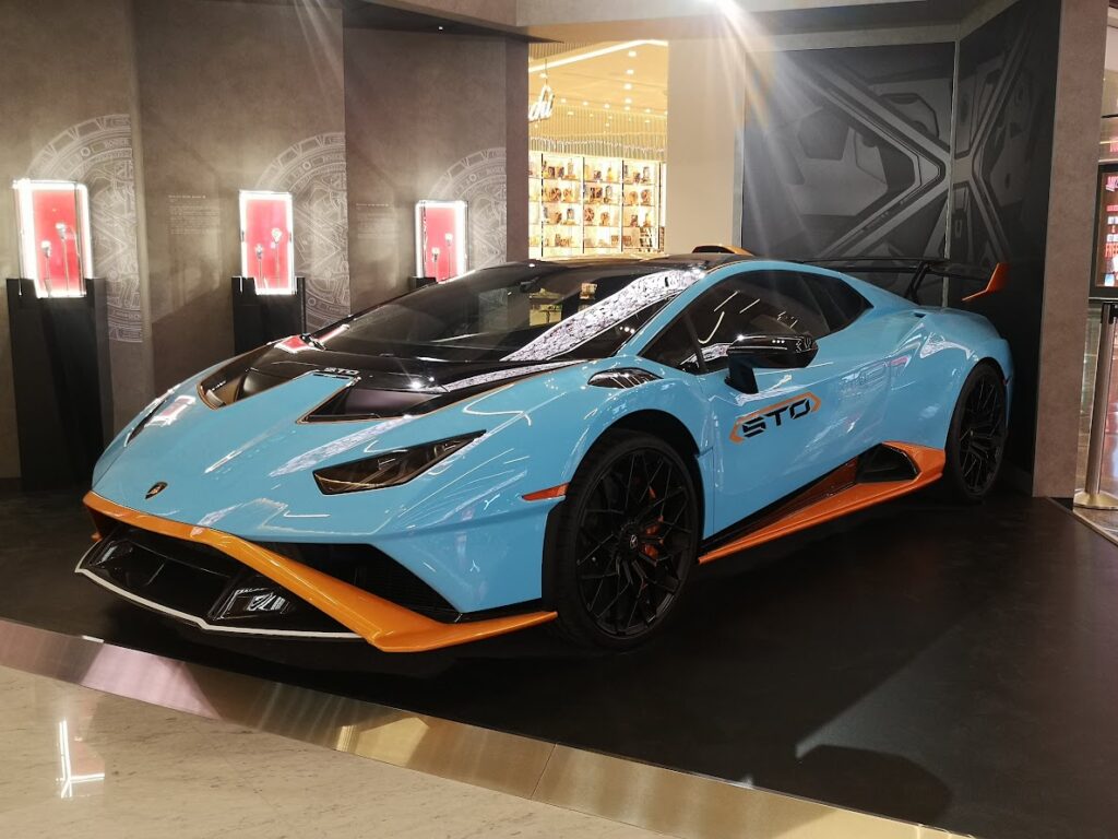 Sleek blue and orange lamborghini sports car on display indoors with luxury features and modern design elements.