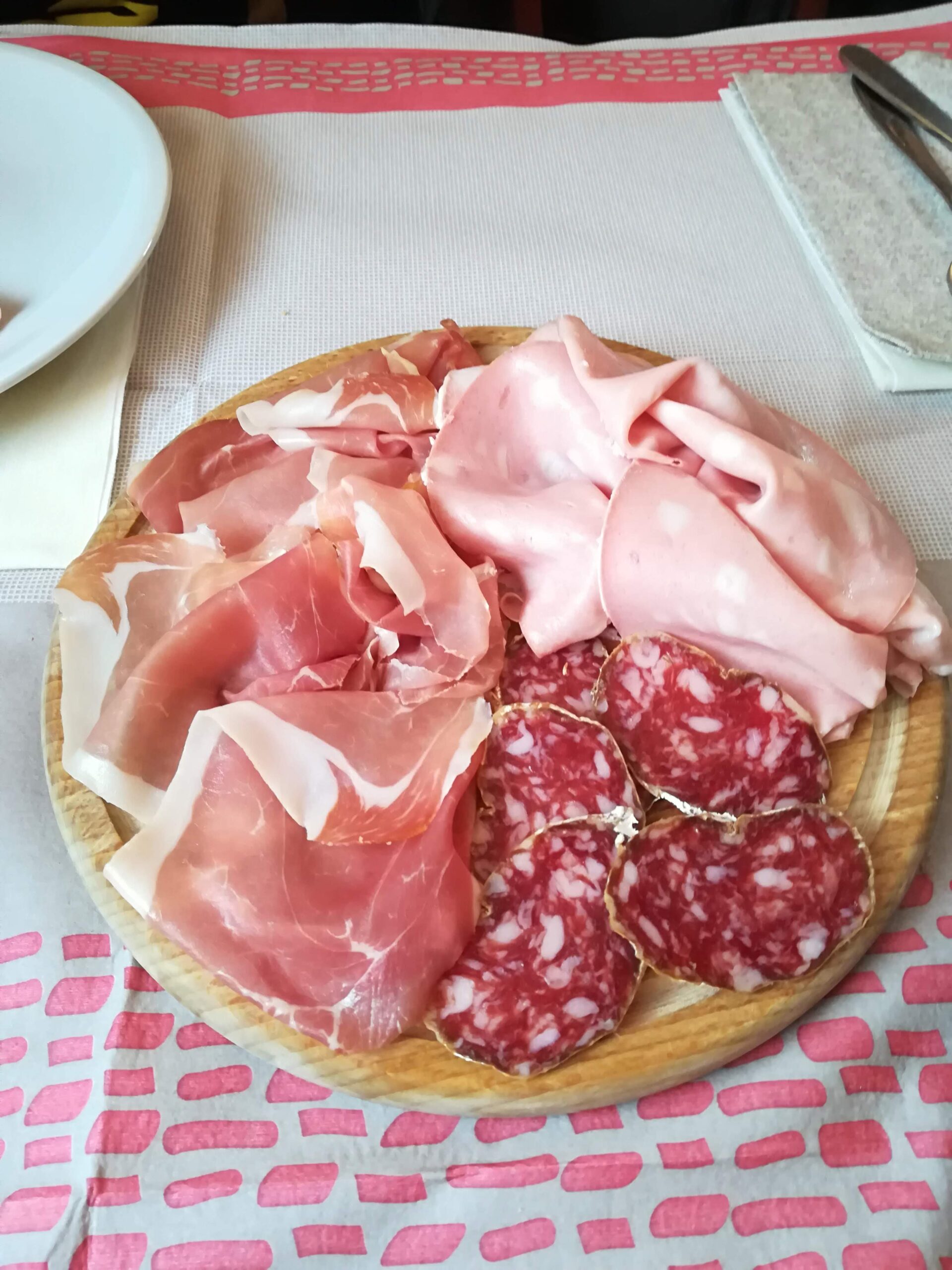 Aufgeschnittener Parmaschinken auf einem Holzbrett — Prosciutto di Parma bei einer Verkostung