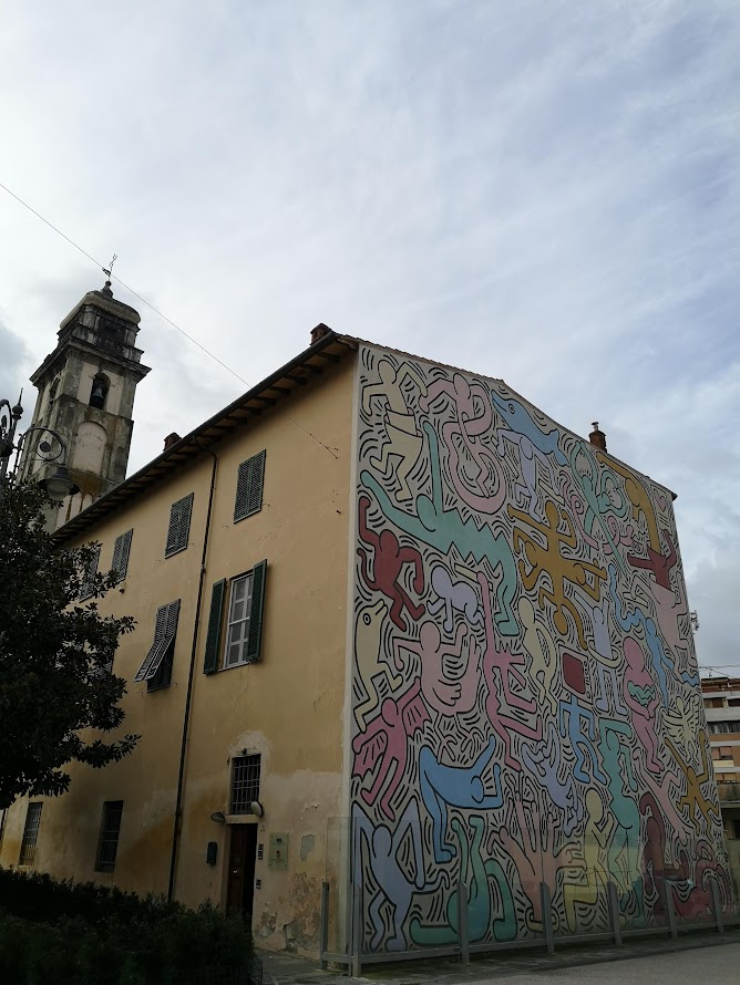 Colourful mural covering an entire building wall in an Italian village — the kind of large-scale outdoor art that defines painted-wall villages in Emilia-Romagna