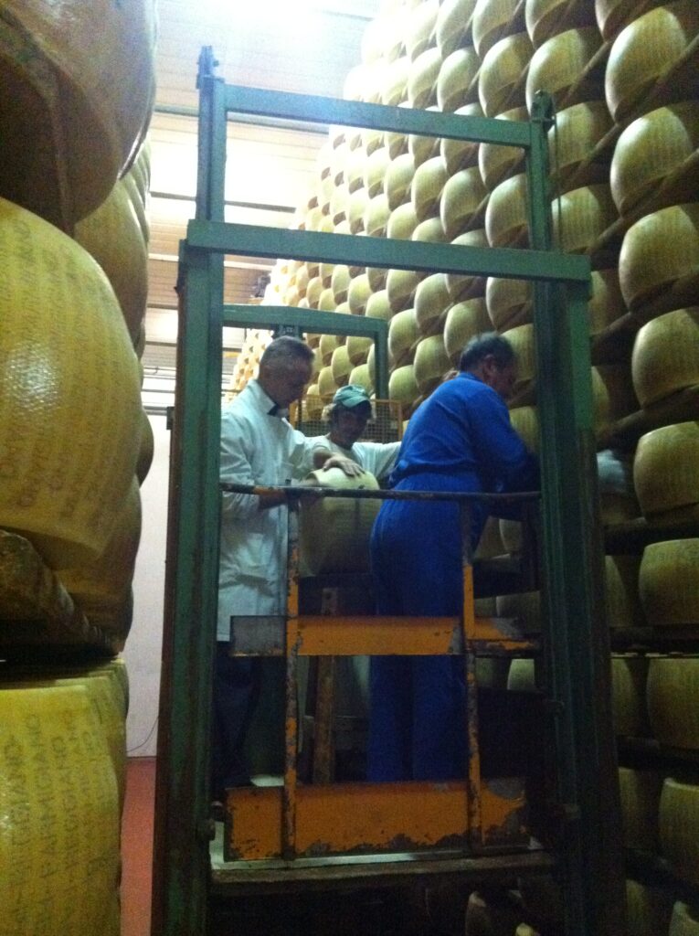 Arbeiter im Reifekeller einer Parmigiano Reggiano Käserei in der Emilia-Romagna